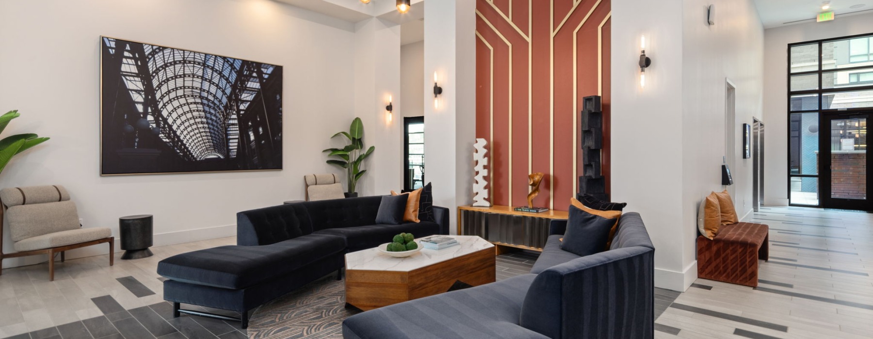 Room with lounge seating and large windows with plants 